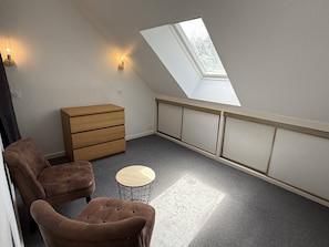 A small room with a sloped ceiling, a wooden dresser, two brown tufted chairs, a round wooden table, and a skylight. - NEW LISTING, Domaine de KER-PAULT, between St Cast and Matignon, apartment 5 minutes from the... (MATIGNON)