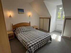 Ein Schlafzimmer mit einem Bett, zwei Nachttischen, einem Kleiderschrank und einem Fenster.