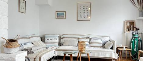 A cozy living room with a sectional sofa, a glass coffee table, a woven basket, and a golf bag.