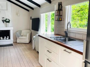 Una cocina moderna con armarios blancos, encimera de madera, pileta integrada y ventana con vista a vegetación.