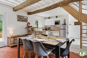 Eine moderne Küche mit weißen Schränken, Holzbalkendecke und einem Essbereich mit Tisch für vier Personen.
