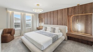 Ein modernes Schlafzimmer mit einem großen Bett, einem Sessel und Blick ins Freie.