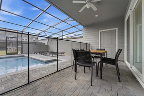 Un patio techado con piscina, una mesa y sillas.