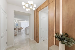 A hallway with a wooden accent wall, a white door, and a plant. - 5BR Home with Pool & Game Room at Windsor Cay (Clermont)