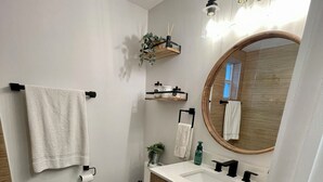 Een badkamer met toilet, wastafel, opbergmeubel, handdoekrek en spiegel.