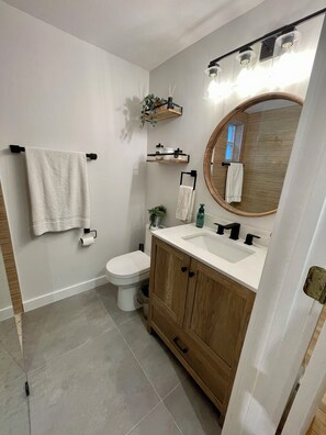Ein Badezimmer mit Toilette, Waschbecken, Ablagefläche, Handtuchhalter und Spiegel.