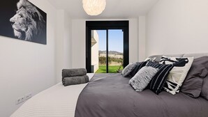 Une chambre moderne avec un grand lit, une vue sur l’extérieur et un luminaire fixé au plafond.