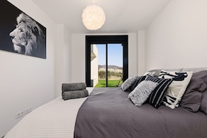Ein modernes Schlafzimmer mit einem großen Bett, Blick ins Freie und einer Deckenleuchte.