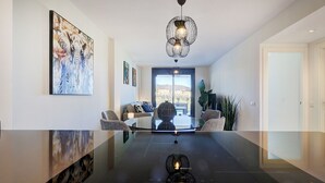 Un intérieur moderne avec une table en verre, un lustre et un tableau représentant des éléphants.