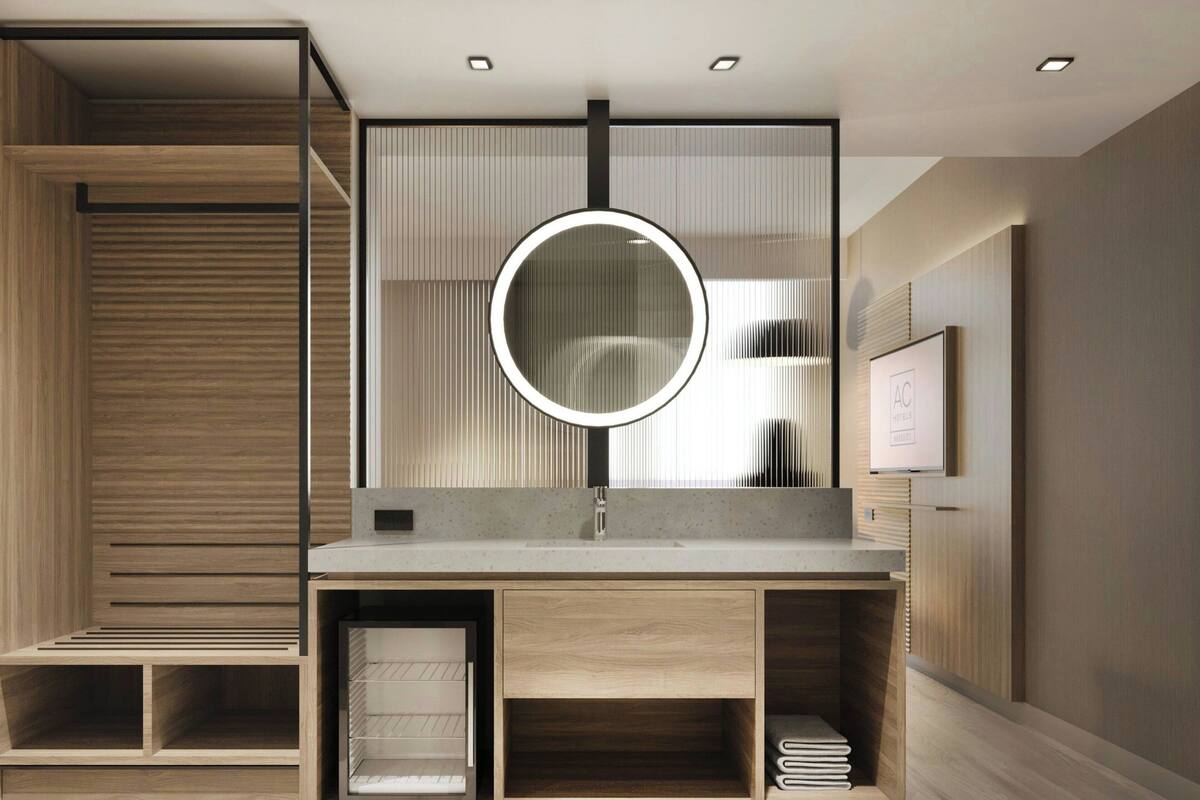 Un baño moderno con un tocador de madera, un espejo redondo y estantes empotrados.