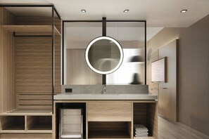 Un baño moderno con un tocador de madera, un espejo redondo y estantes empotrados.