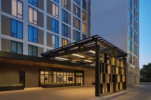A modern hotel entrance with a covered outdoor area, large windows, and a clear sky. - AC Hotel Denver RiNo (Denver)