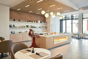 A modern kitchen with a central island, wooden paneling, and a variety of kitchenware on shelves. - AC Hotel Denver RiNo (Denver)