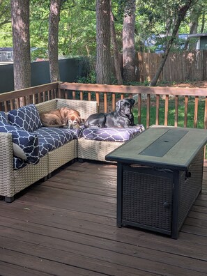 Eine Holzterrasse mit einem Korbsessel und einem schwarzen Tisch.