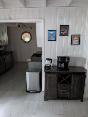 A kitchen with a refrigerator, coffee maker, and a cabinet. There are framed pictures on the wall. - 3BR Decatur Home - Avondale Train to Stadium/Downtown (Decatur)