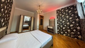 A bedroom with a bed, a dresser, a mirror, and a chandelier. - Spacious 7-bedroom house in peaceful Baku with AC (Baku)
