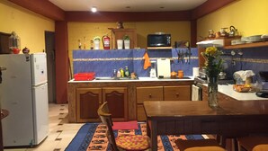 Una cocina con refrigerador, microondas, lavamanos y armarios de madera.