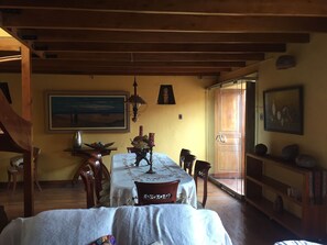 Ein Essbereich mit Tisch für vier Personen, Holzsesseln, einer Kandelaber und einem Bild an der Wand.