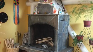 Una chimenea con un fuste decorativo, suelo a cuadros y una planta en maceta.
