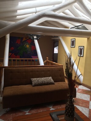 Ein modernes Interieur mit einem braunen Sofa, einer dekorativen Vase und einem farbenfrohen abstrakten Gemälde an der Wand.