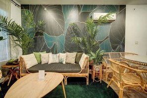 Ein Zimmer mit einer Couch, Stühlen, einem Tisch und Topfpflanzen.