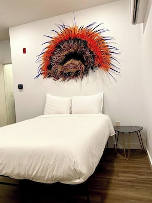 Ein Hotelzimmer mit einem Bett, einem kleinen runden Tisch und einem Wandbild.