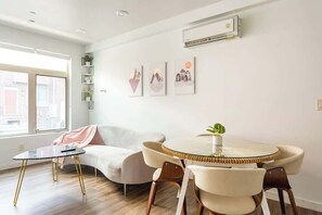 Ein modernes Wohnzimmer mit einem runden Esstisch, einer Couch und einem kleinen Beistelltisch.