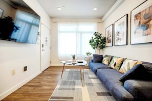Ein modernes Wohnzimmer mit einer Couch, einem Couchtisch und einem an der Wand montierten Fernseher.