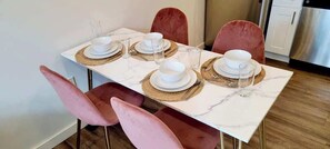 Ein Esstisch mit Geschirr, Schüsseln und Besteck, umgeben von rosafarbenen Stühlen.