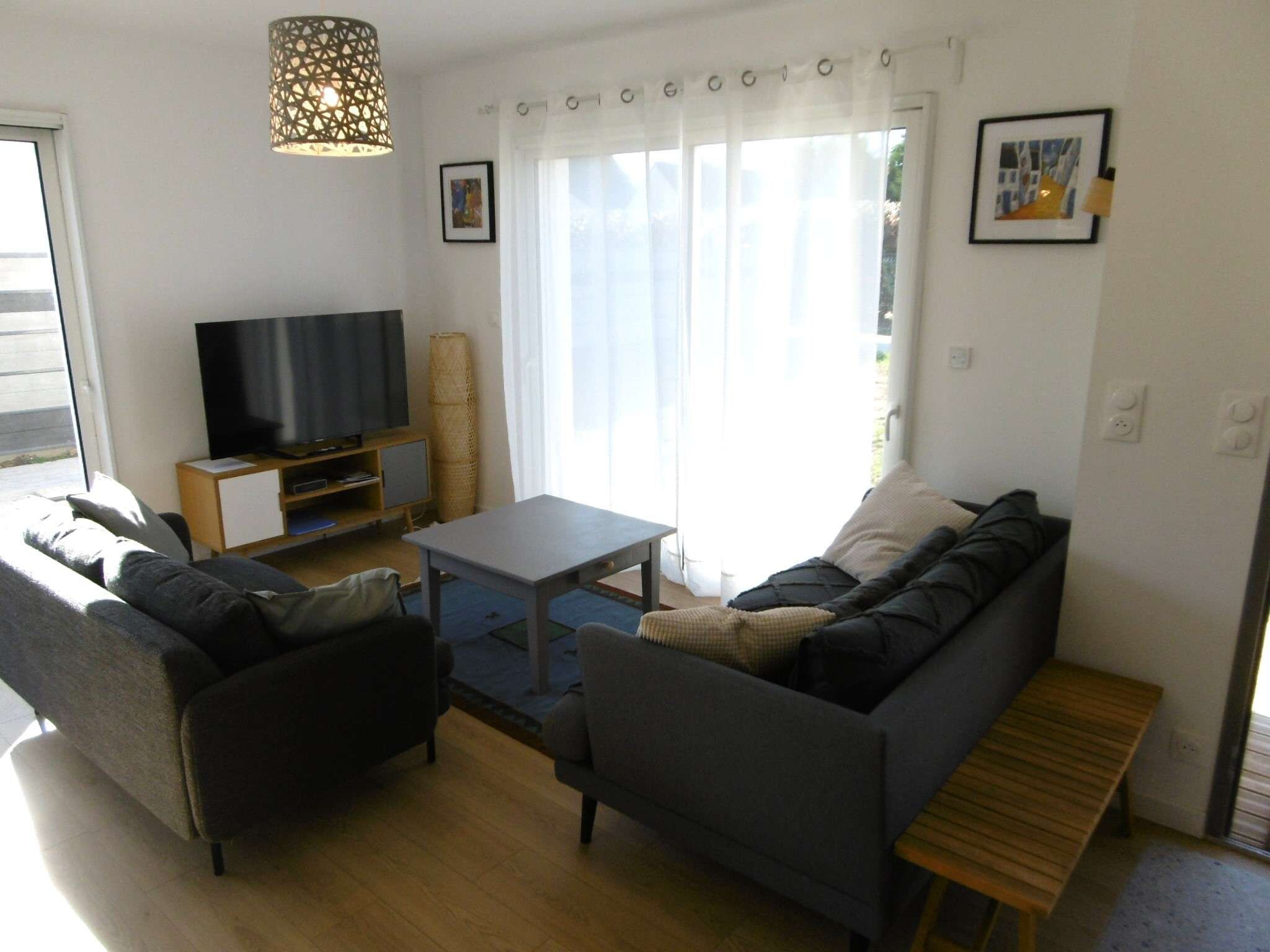 A living room with a sofa set, a television, a coffee table, and a lamp.