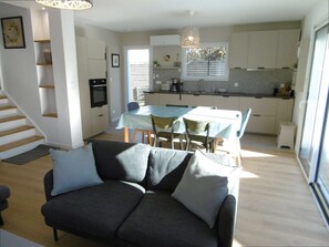A modern interior with a sofa, dining table, and kitchen area. - House 4 rooms 6 to 8 people near the sea (SARZEAU)
