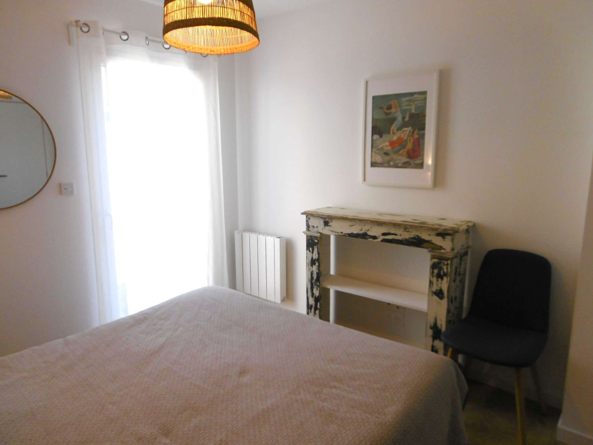 A bedroom with a bed, a chair, a table, and a painting on the wall.