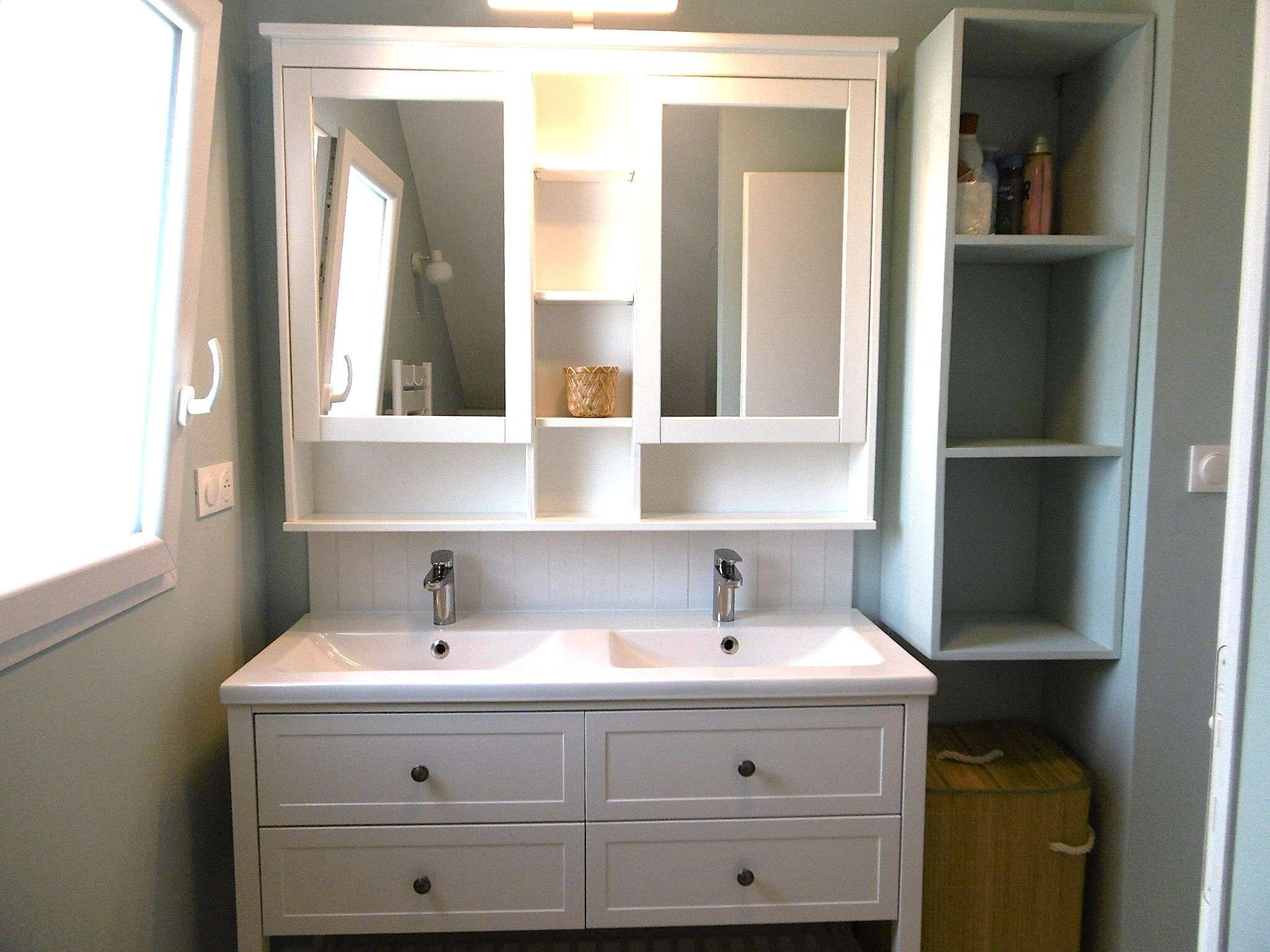 A bathroom with a double sink vanity, a large mirror, and a shelf with toiletries.