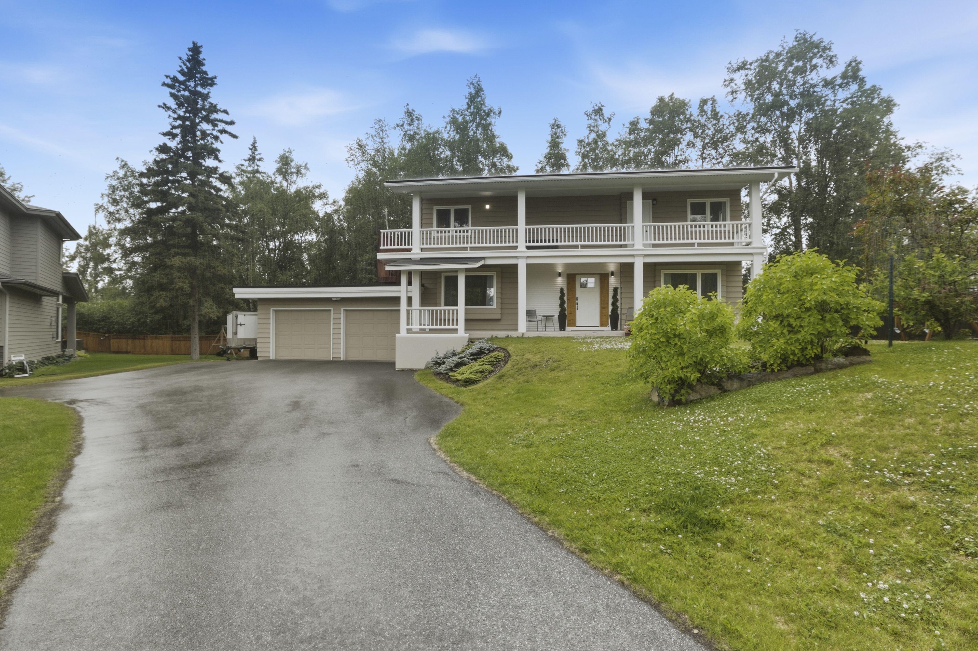 A two-story house with a front porch, a garage, and a driveway leading to the entrance.