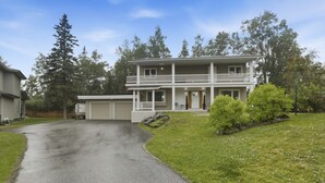 A two-story house with a front porch, a garage, and a driveway leading to the entrance.
