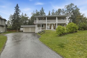 A two-story house with a front porch, a garage, and a driveway leading to the entrance.
