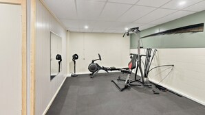 A gym with exercise equipment, a mirror, and a wall-mounted fan.