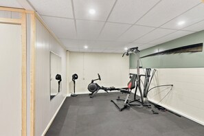 A gym with exercise equipment, a mirror, and a wall-mounted fan.