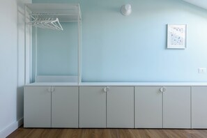 Ein Zimmer mit integriertem Kleiderschrank, einer Kleiderstange und einem gerahmten Bild an der Wand.