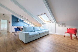Ein modernes Loft mit einem blauen Sofa, einem roten Sessel und einer Küchenzeile.