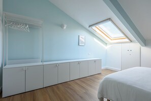 Una camera da letto con soffitto spiovente, una luce sul tetto, un armadio e un letto.