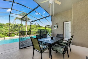 En overdækket terrasse med pool, udendørs møbler og en dør.
