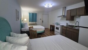 A compact room with a bed, a small dining table, a kitchenette, and a separate sleeping area.