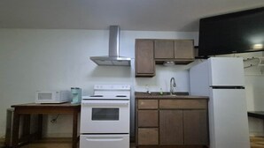 A compact kitchen with a stove, microwave, sink, and refrigerator.