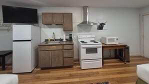 Una cocina compacta con refrigerador, estufa, microondas y armarios de madera.