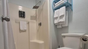 Un baño con ducha, inodoro y perchero para toallas.