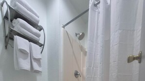 Et badeværelse med toilet, brusebad og et håndklædestativ.