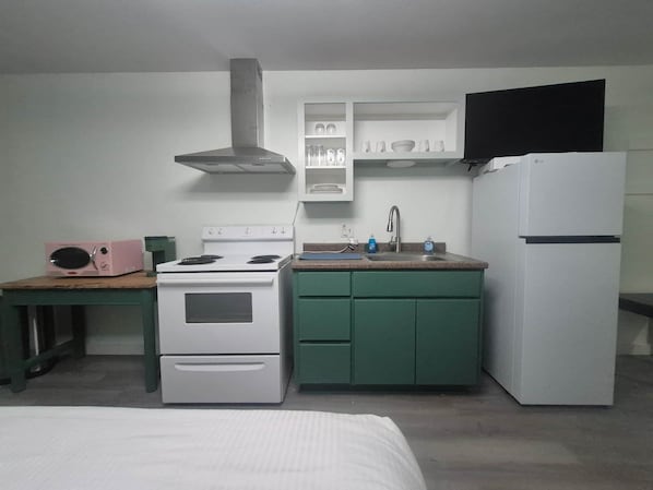 Pieni, käytännöllinen keittiö, jossa on liesi, pesuallas ja jääkaappi.