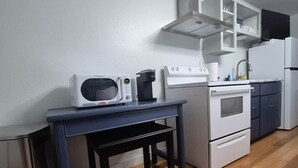 Una cocina equipada con microondas, cafetera, estufa y armarios.