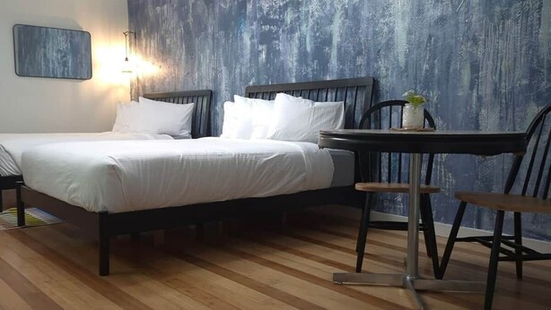 Un dormitorio con cama, mesita de noche, silla y una pared con diseño texturizado.